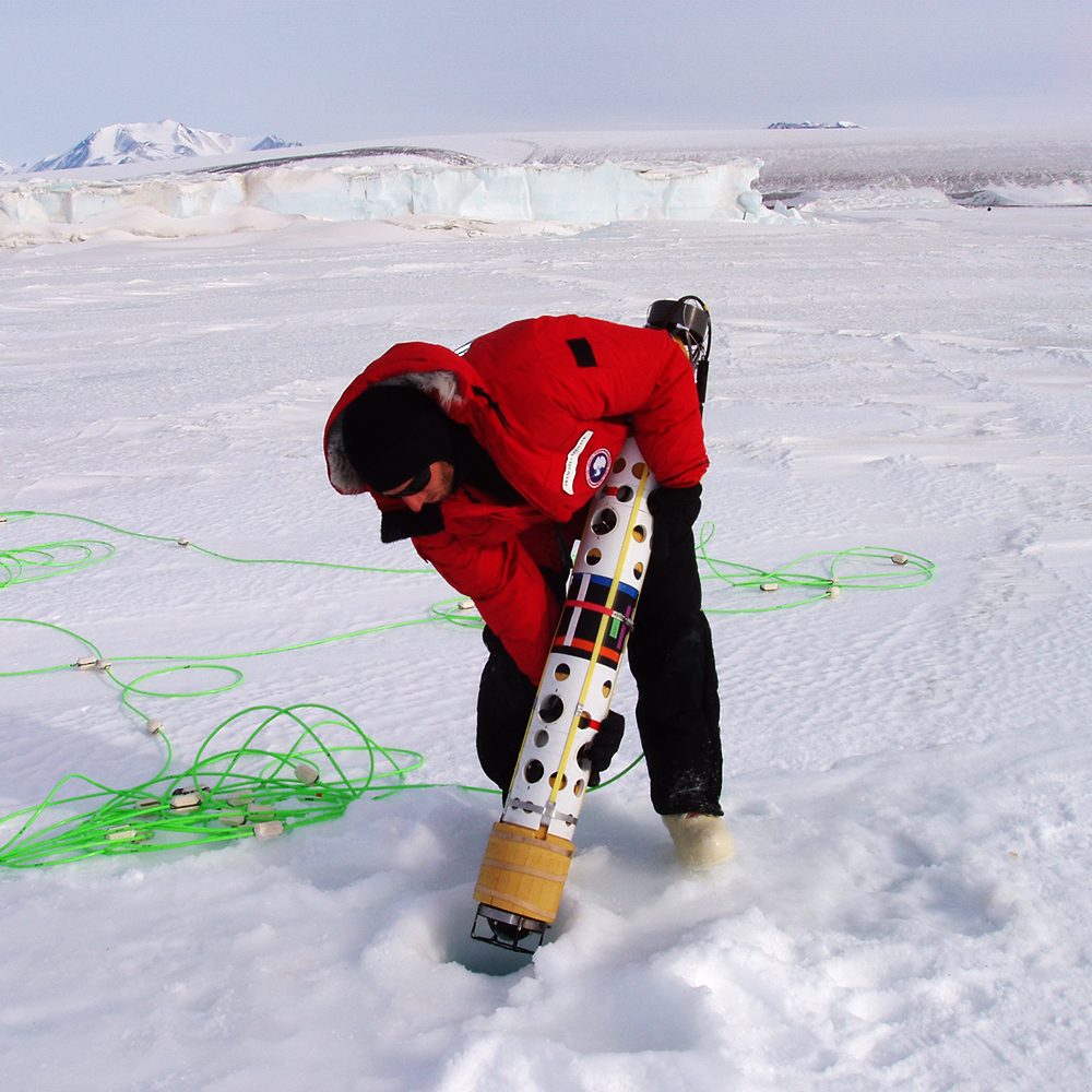 Deploying a remotely operated vehicle under the ice in Antarctica to study the effects of iceberg scour on benthic organisms.