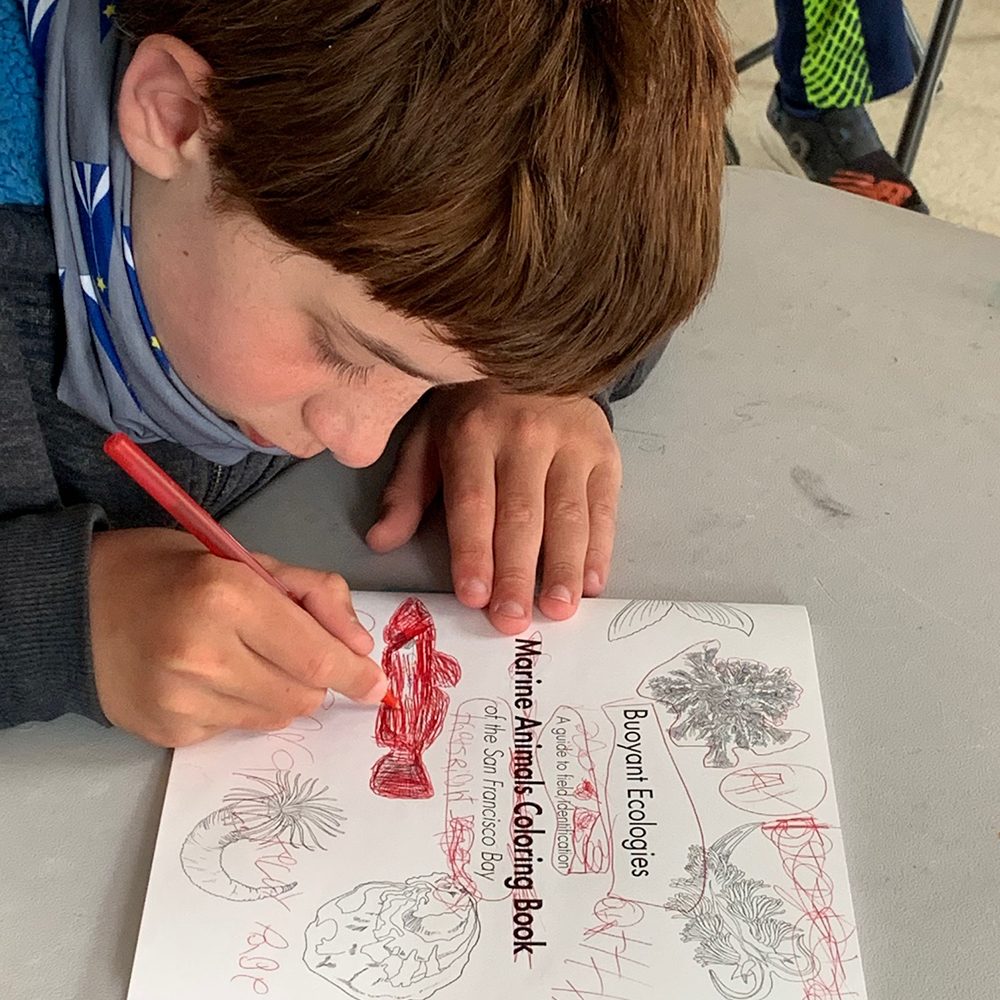 A student works on his educational coloring book created in collaboration with staff and students at California College of the Arts.